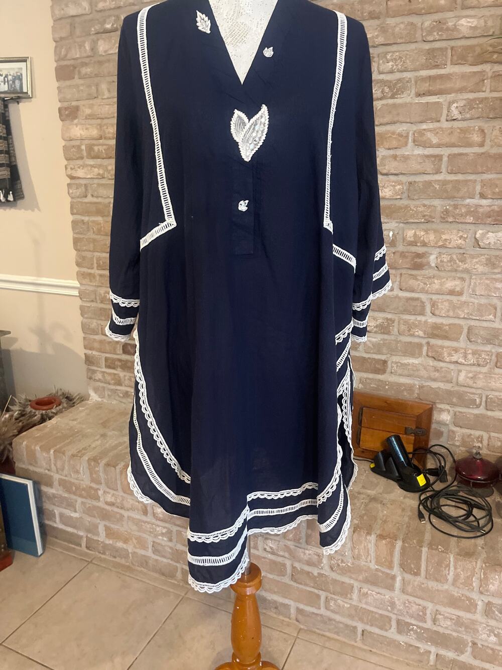 Navy tunic featuring intricate floral lace trim on neckline, hem & sleeves.